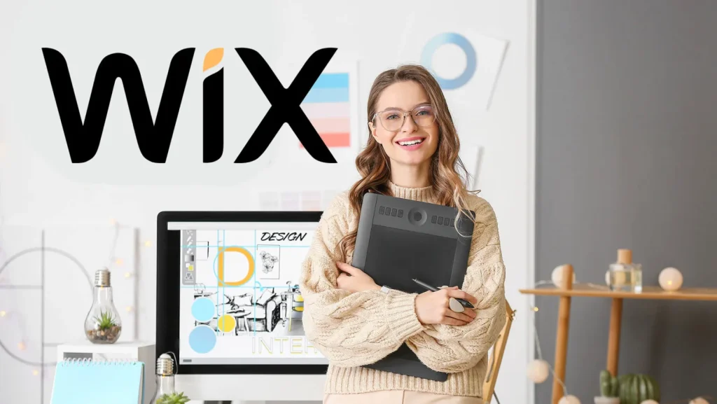 Wix logo beside a smiling designer holding a graphics tablet in a studio with a design workstation behind her